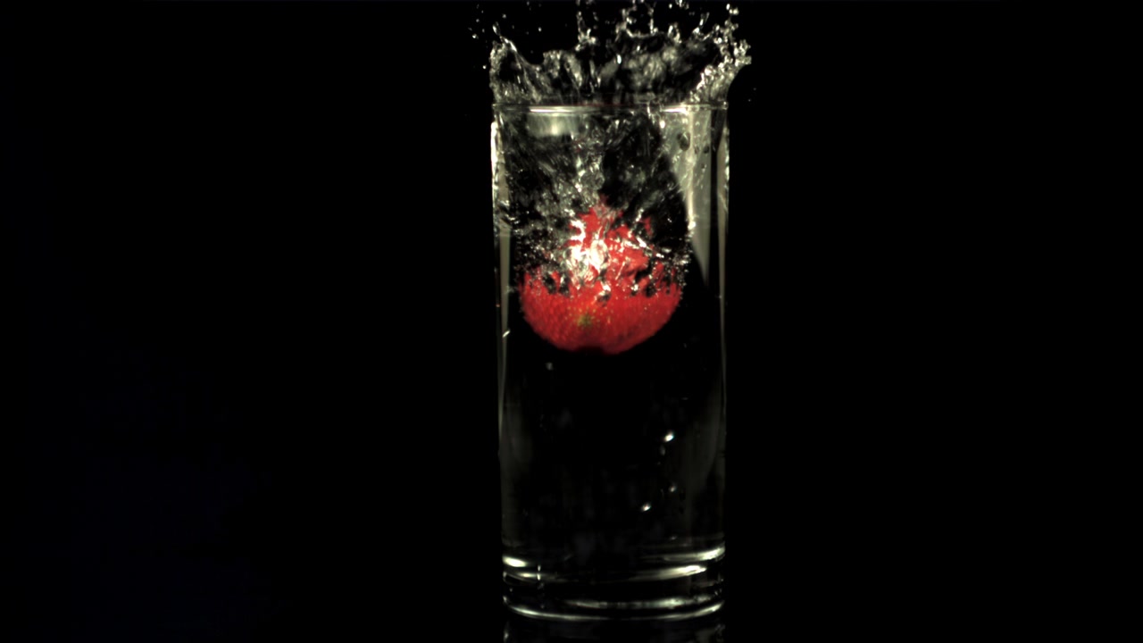 Fragola rossa che cade in un bicchiere d'acqua al rallentatore