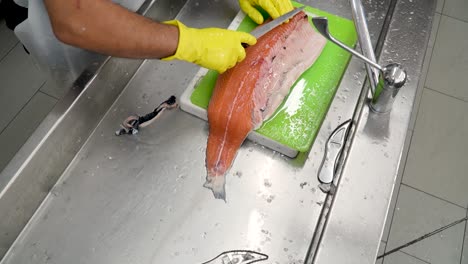 a skilled fishmonger prepares a large salmon using precise techniques in a bustling seafood market kitchen. the process showcases expert knife skills and careful handling