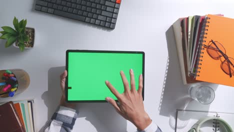 vista de arriba hacia abajo de una computadora portátil con pantalla verde simulada pantalla chromakey en un escritorio de oficina de madera al lado de la libreta con bolígrafos, gafas y un vaso de agua.