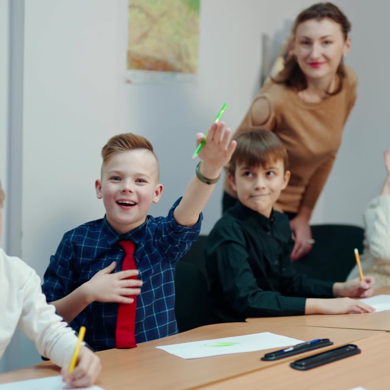 Children study at primary school. All kids rise hands up to answer during the lesson in the classroom. Elementary education concept.