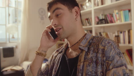 young handsome man sitting at home and chatting on mobile phone