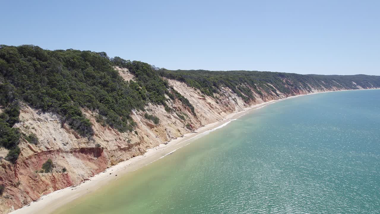 arena blanca y costa escarpada con vegetación en la playa del arco iris en la región de gympie, queensland
