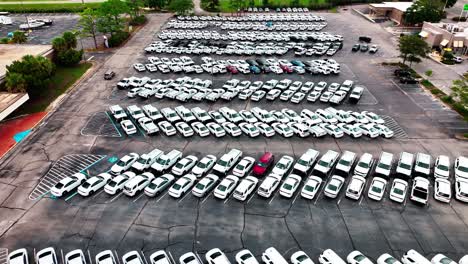 Volando-Bajo-Sobre-Un-Estacionamiento-Lleno-De-Coches-De-Policía-Camuflados,-Vehículos-Blancos-Y-Plateados.