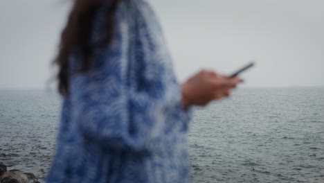 woman using phone by the ocean