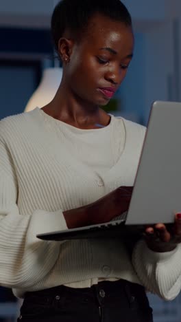 vertical video exhausted business woman holding laptop, typing and sighing looking at camera