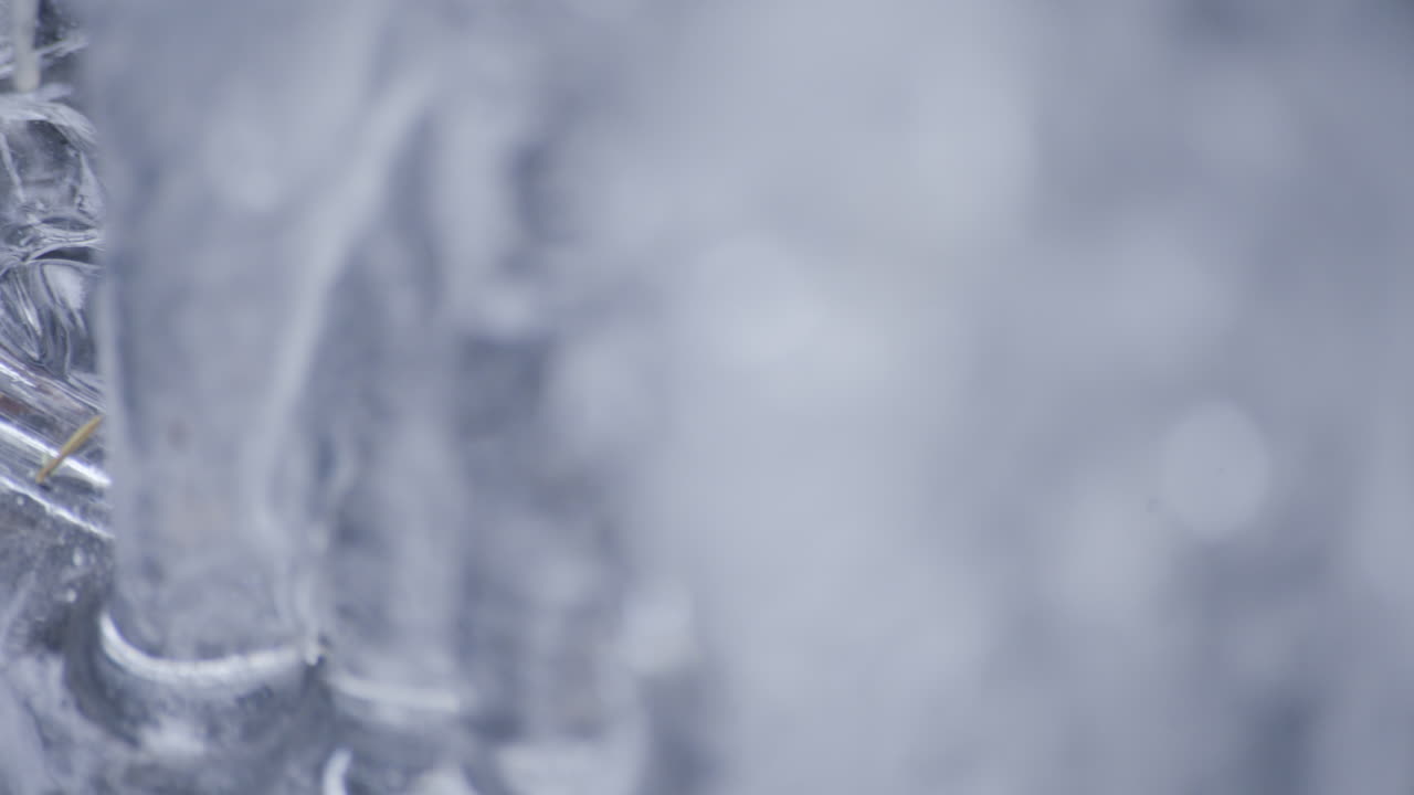 scatto macro di ghiaccioli e acqua che scorre sotto un ruscello ghiacciato