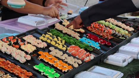 hands arranging assorted sushi on multiple platters