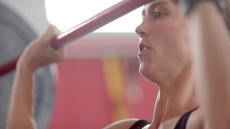 joven mujer caucásica en forma hace ejercicios en el gimnasio, levantando pesas