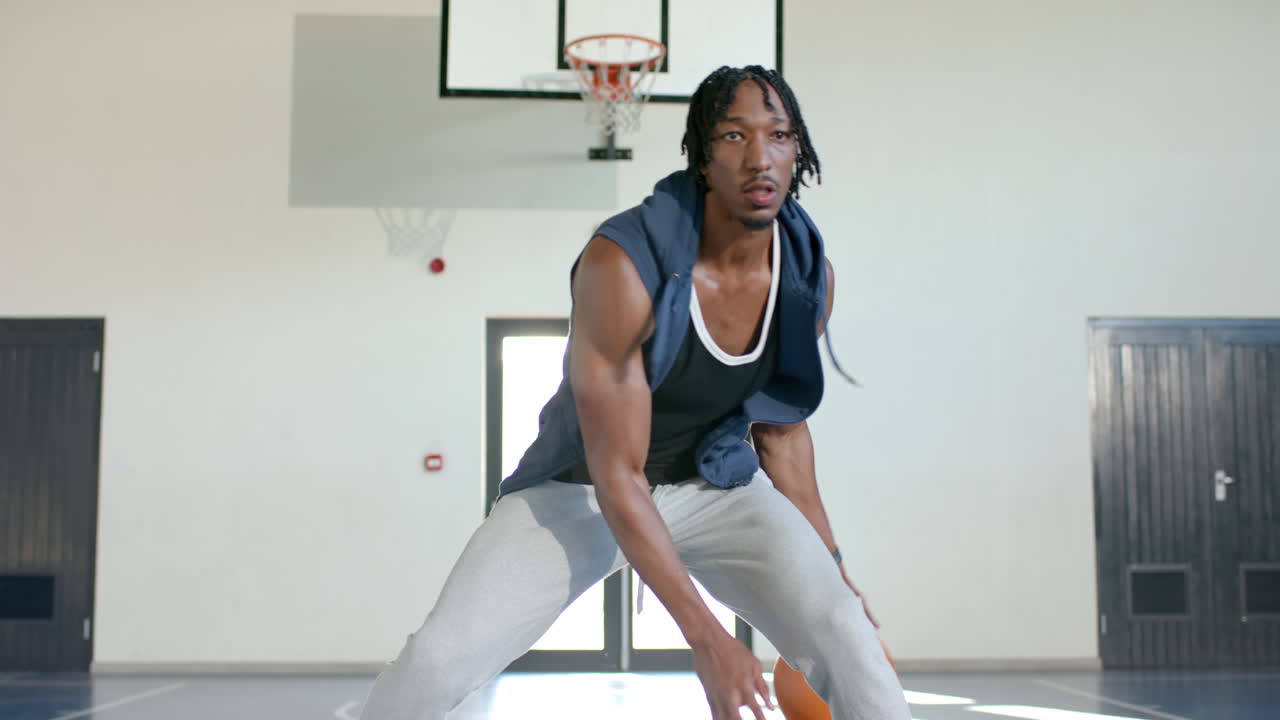 Playing basketball, man dribbling ball on indoor court, focusing on game, copy space