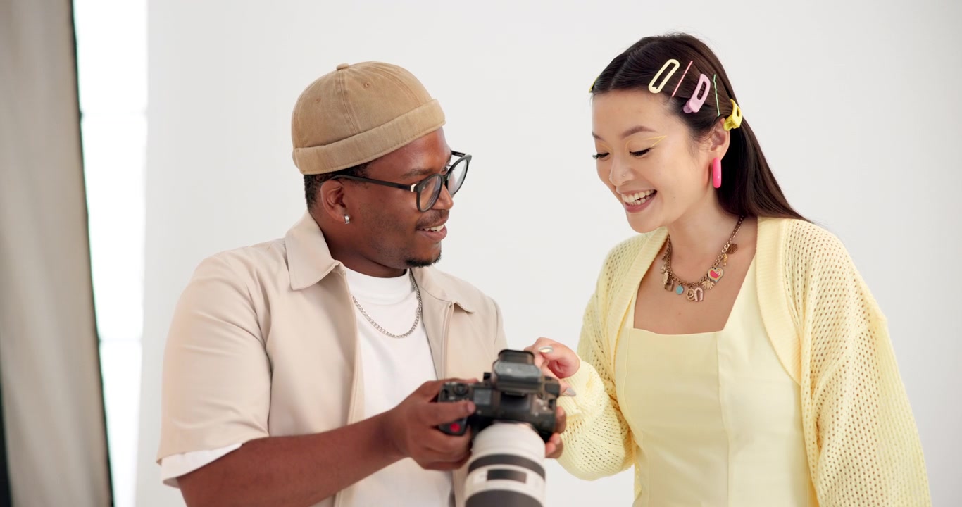 Fotografo e modella controllano le foto sulla fotocamera in studio