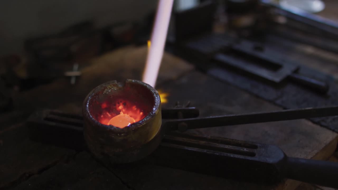 Primer plano de la llama de un soplete de gas fundiendo metal para joyería.
