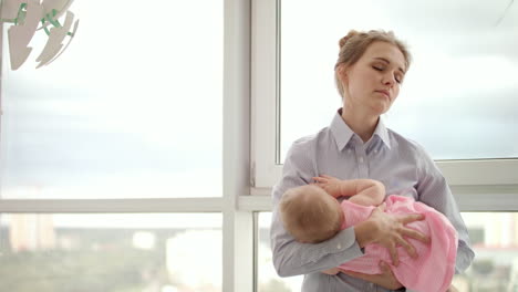 madre cansada sosteniendo al bebé en las manos cerca de la ventana. madre de negocios llevando al bebé
