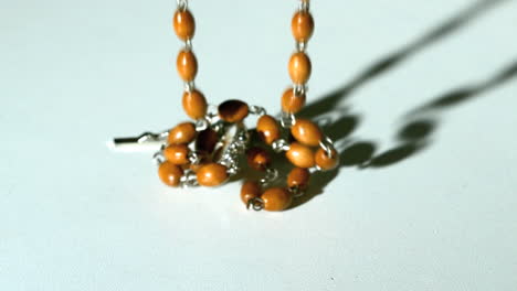 Rosary-beads-casting-a-shadow-and-then-falling