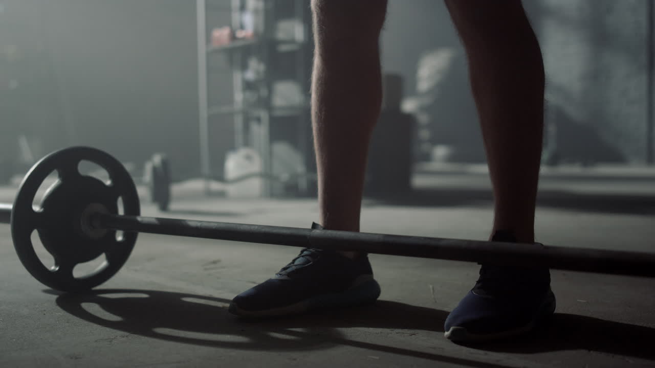Atleta che prepara l'attrezzatura sportiva per l'esercizio. Uomo che mette i dischi sul bilanciere.