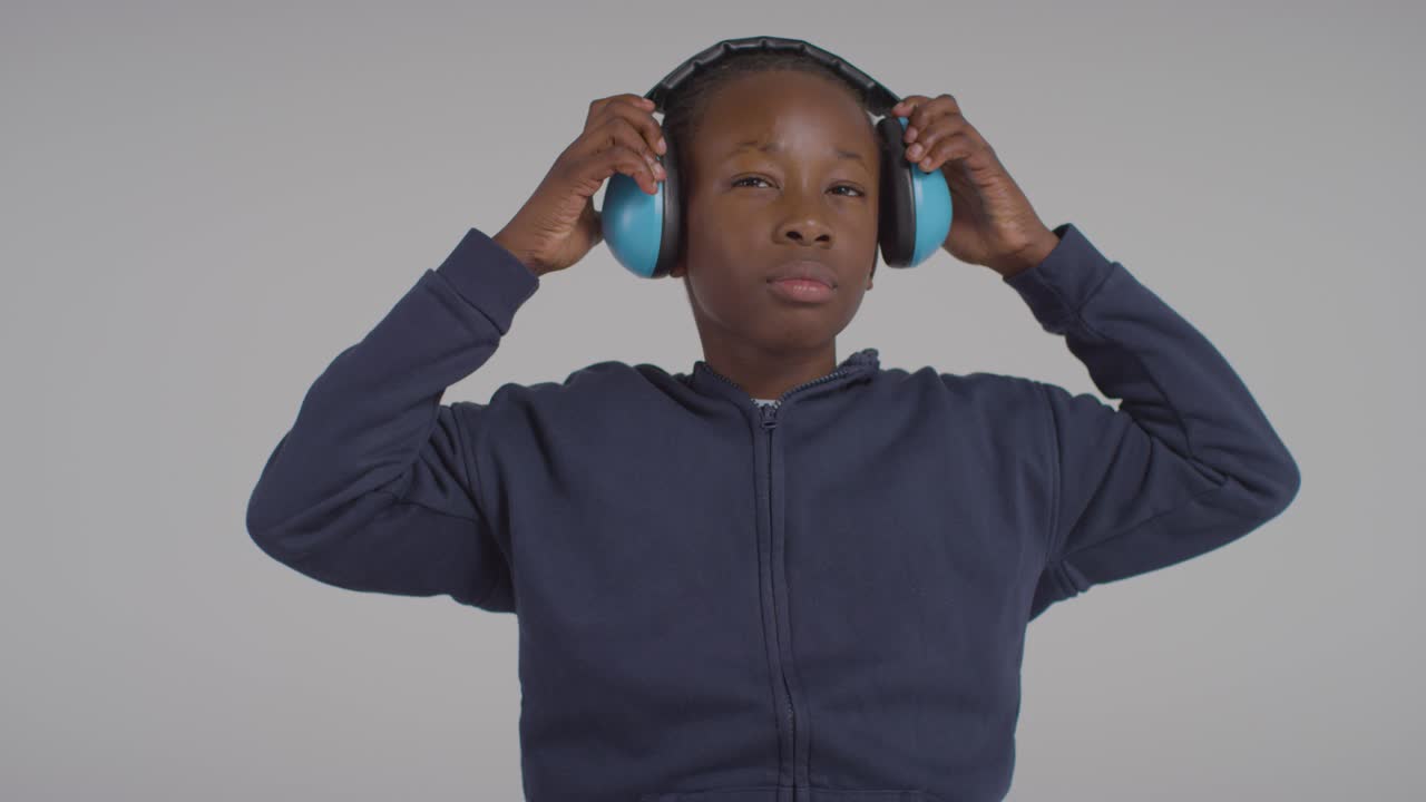 Studio Shot Of Boy On ASD Spectrum Showing Sensitivity To Loud Noises Or Sounds Wearing Ear Defenders 2