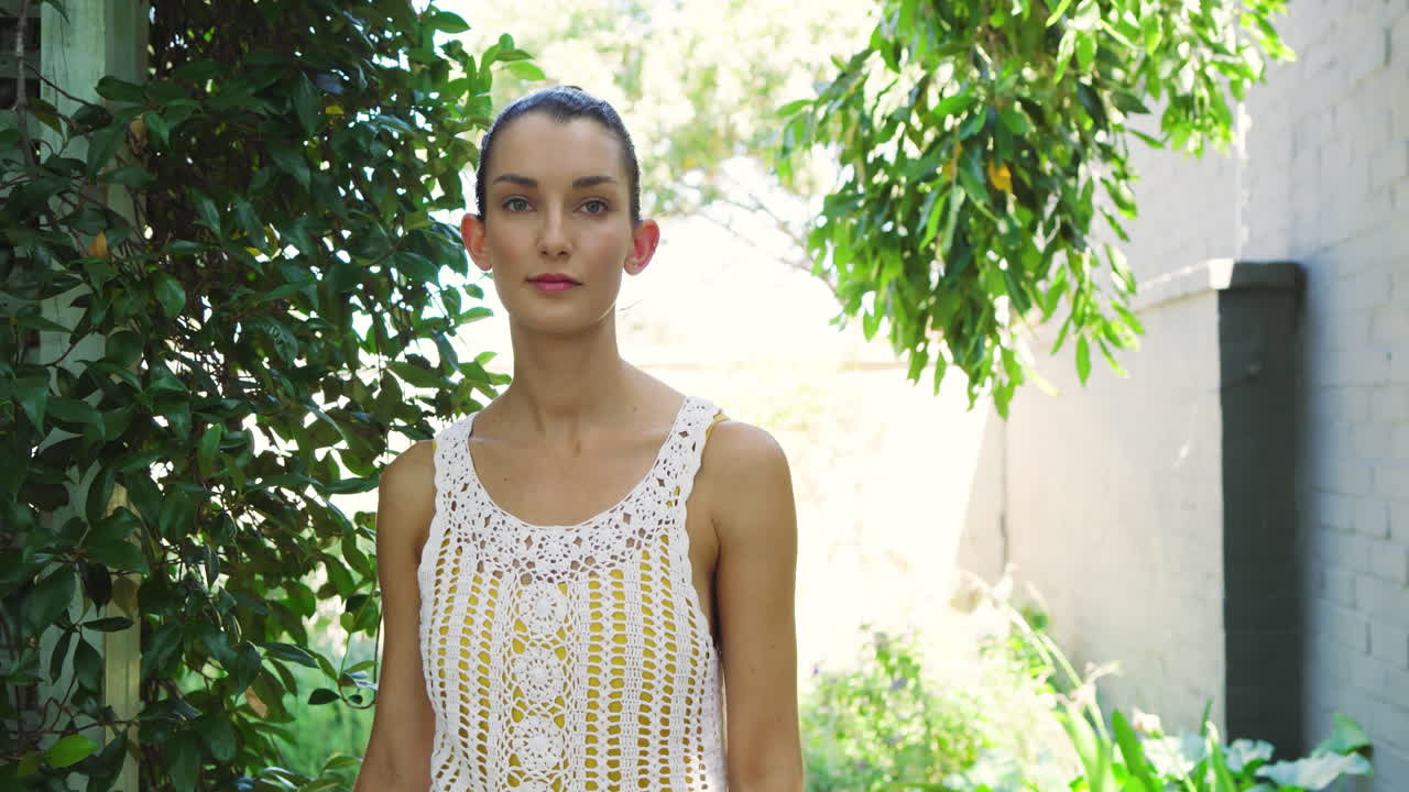 Smiling woman in crochet top standing outdoors surrounded by lush greenery
