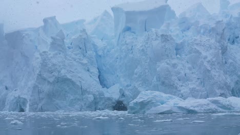 Sailing-Under-Massive-Glacier-on-Coast-of-Antarctica-on-Snowy-Day,-Close-Up