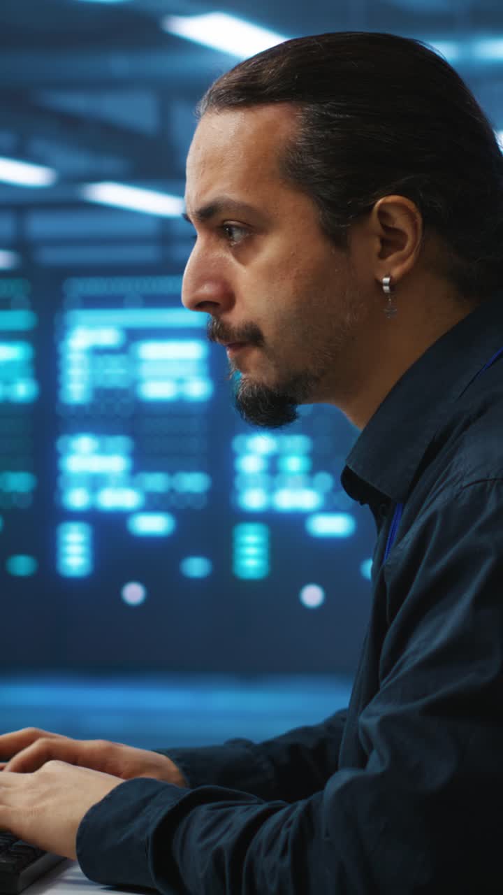 Fokusert mann som skriver på datamaskin i datasenter