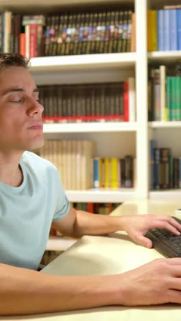 man working at desk with bookshelf