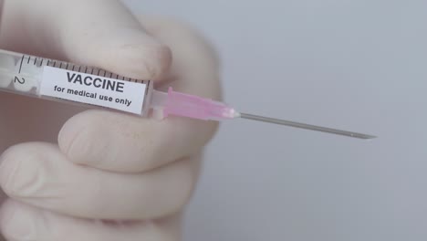 un médico empuja el émbolo de la inyección con la vacuna, primer plano