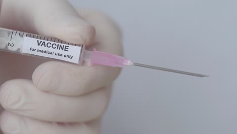 a doctor push the plunger of injection with vaccine, close up shot