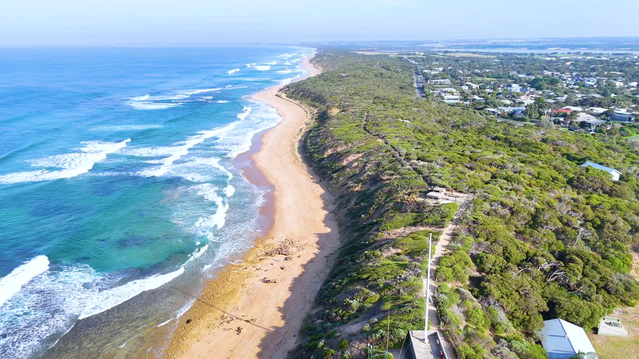 Aerial footage of Point Lonsdale's coastline, showcasing the lighthouse, beach, and ocean under bright daylight