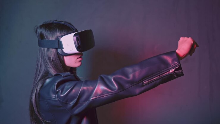 Giovane donna con una giacca di pelle si diverte con un visore per la realtà virtuale e cerca di toccare qualcosa