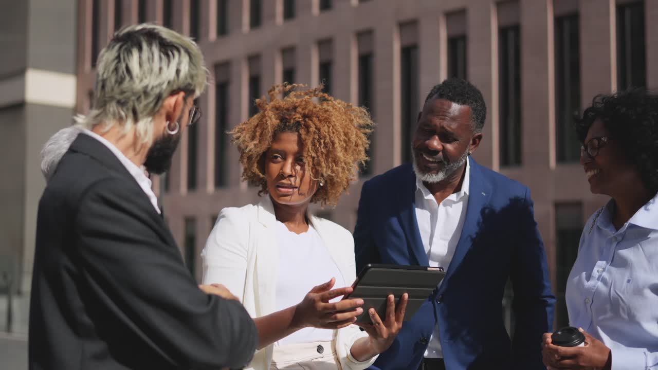 Business people exchanging ideas in an outdoor meeting using tablet