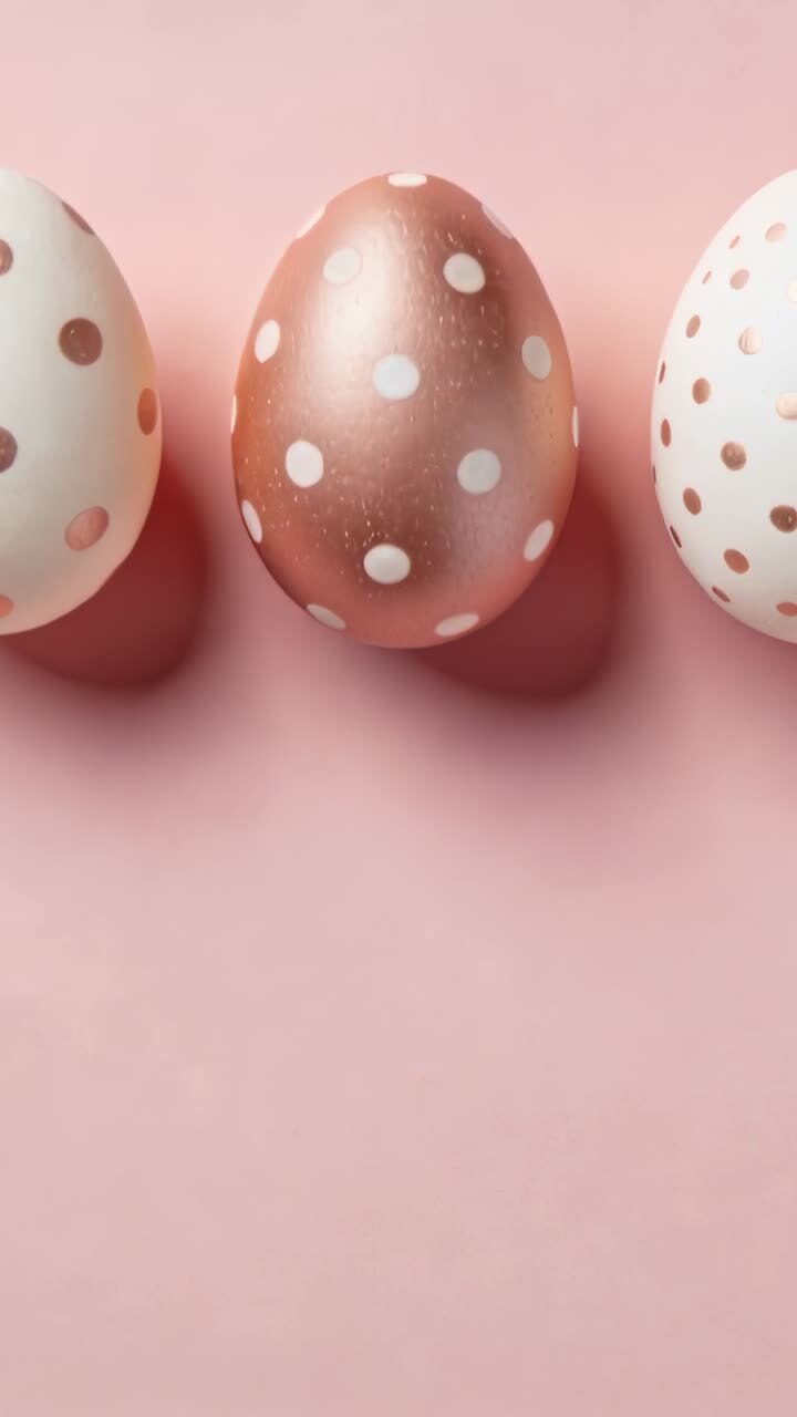 Shifting camera showing central metallic rose-gold egg on pastel pink backdrop, with two white eggs