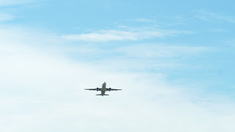 an airplane captured from its underside as it is taking off revealing a blue sky and clouds, airport in thailand