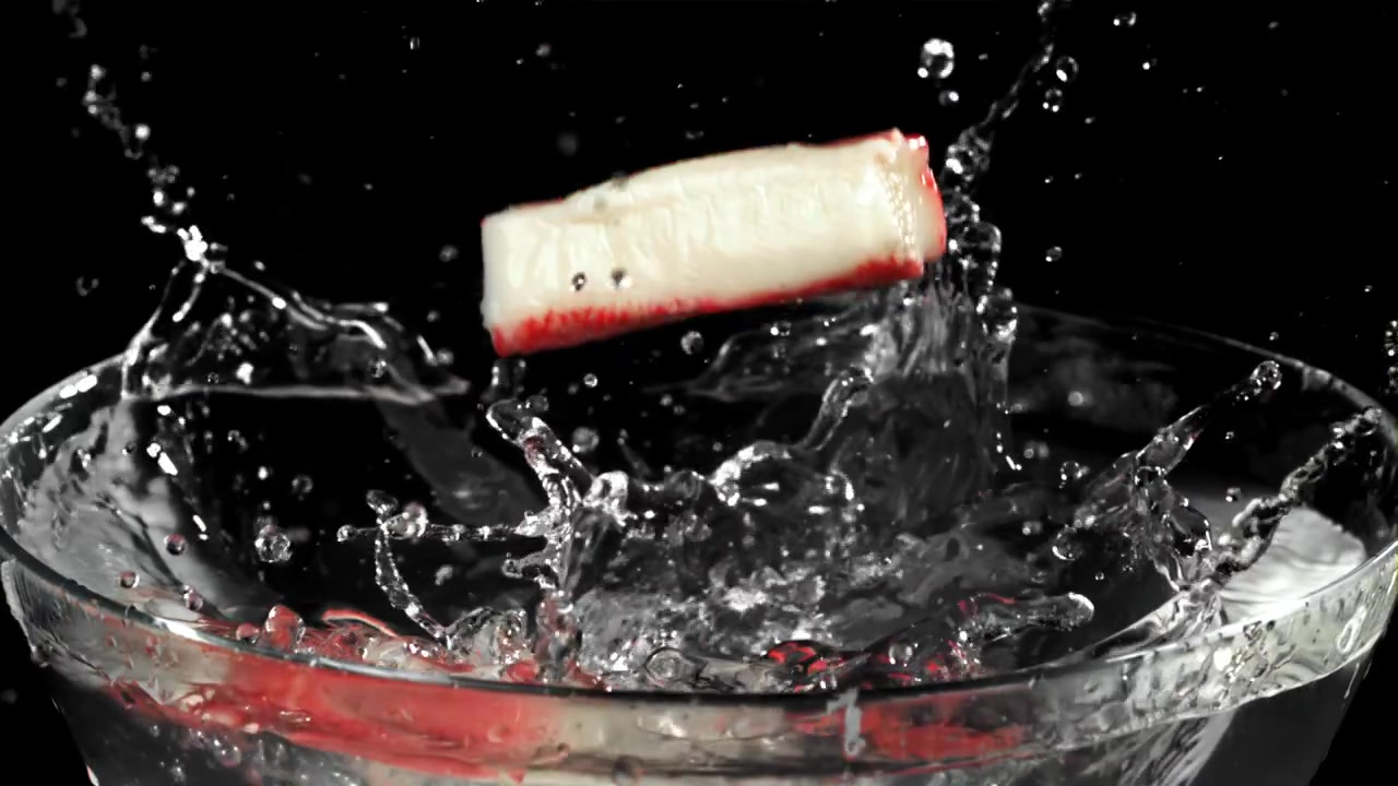 Bastoncini di surimi freschi che schizzano nell'acqua in una ciotola di vetro