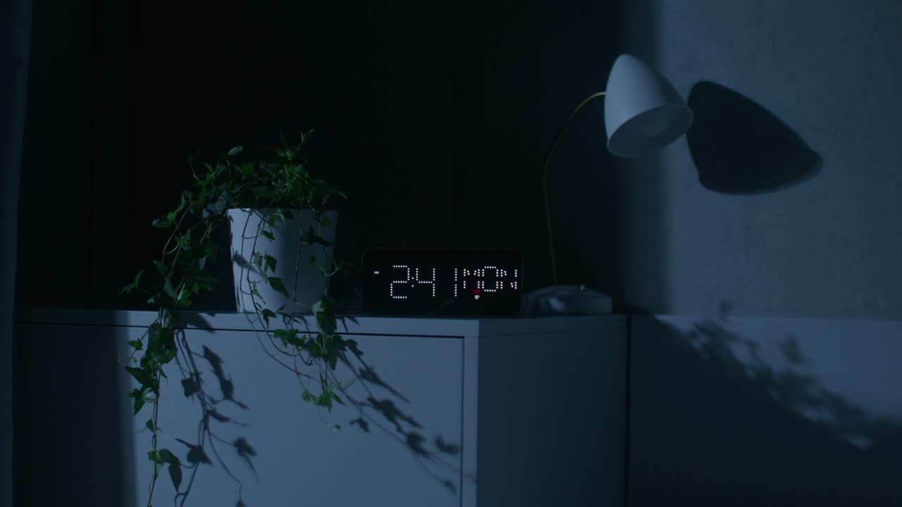 Soveværelsesscene om natten med digitalt ur og plante