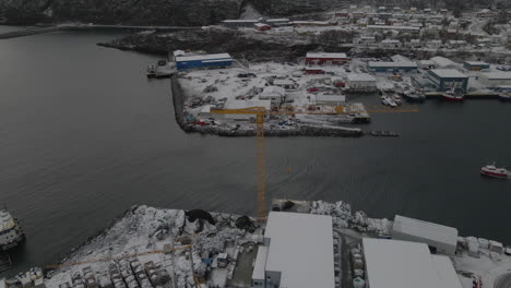 Fishing-vessel-exiting-snow-covered-harbour-in-Scandinavia,-freezing-winter