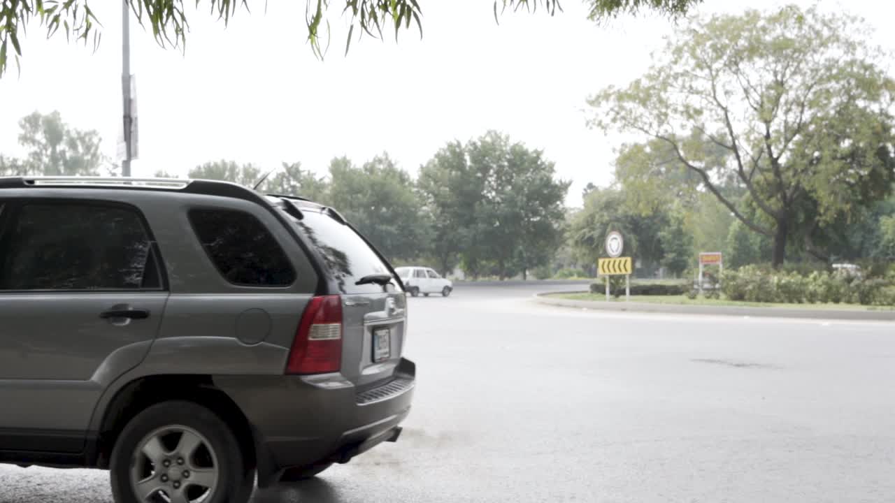 A view of a traffic roundabout with its sign in slow motion as traffic moves.
