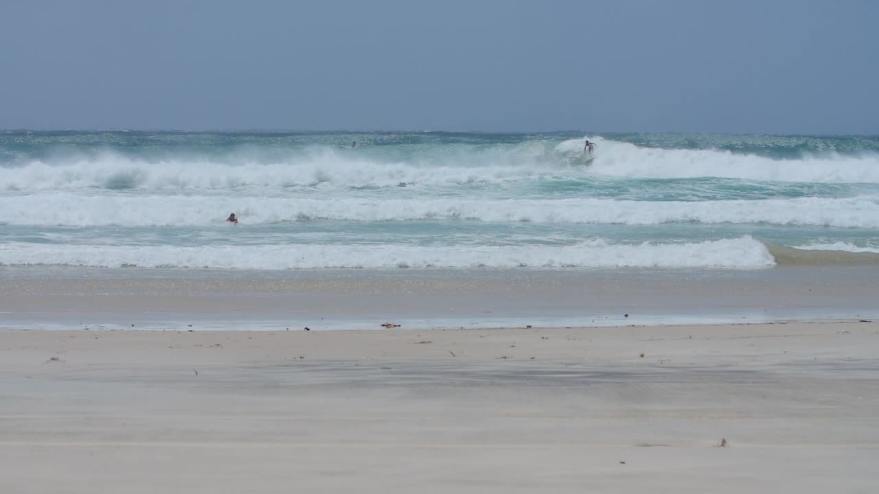 멀리서 볼 수 있는 서퍼가 긴 파도를 타고 있다
