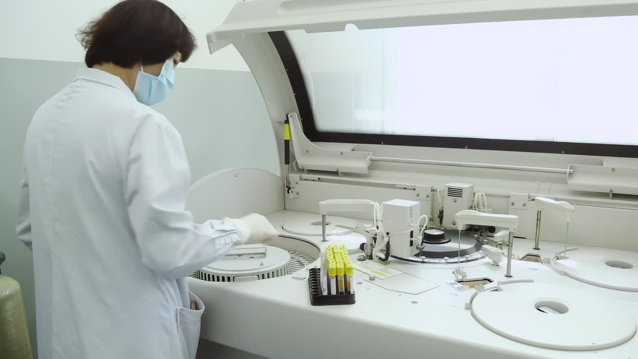 Technician taking blood tubes put into specimens in chemistry test analysis machine in laboratory centrifuge, hand of a doctor or nurse holds a blood test tube