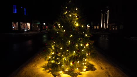 toma aérea de aumento cinematográfico lento del árbol de navidad iluminado con luces en la noche