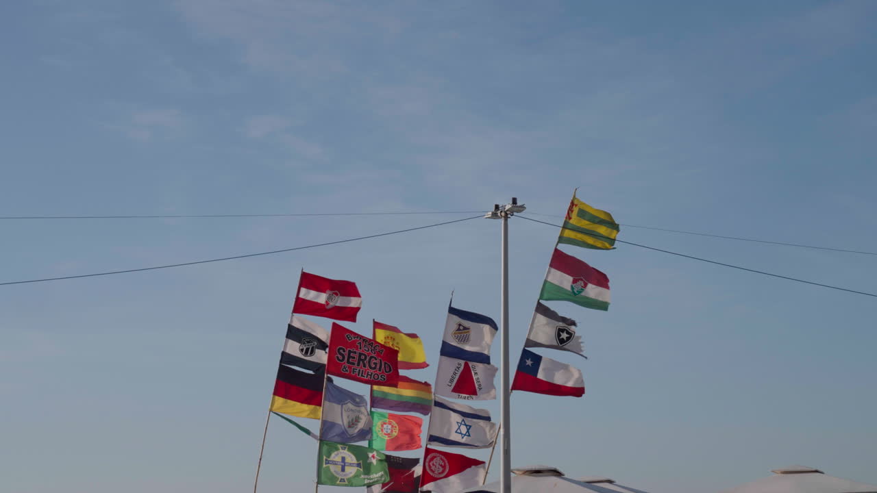 tiros de banderas de países y clubes de fútbol del mundo revolotean en postes soplados por la brisa del mar