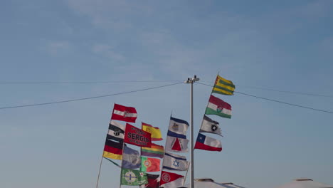 tiros de banderas de países y clubes de fútbol del mundo revolotean en postes soplados por la brisa del mar