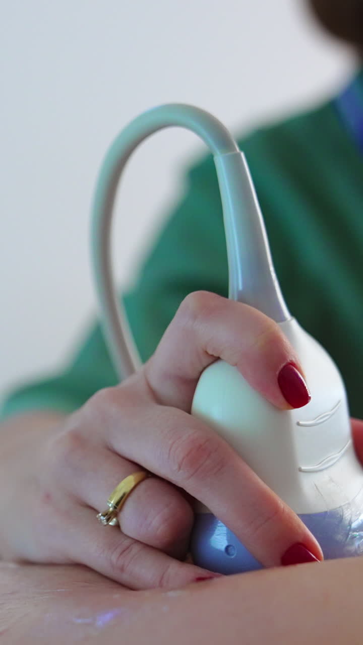 Doctor pressed ultrasound device to a pregnant belly. Close up. Future mom at obstetrician's examination. Vertical video