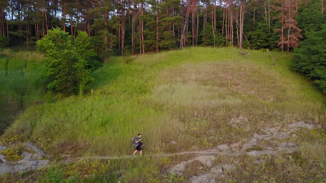 Hiking Man In Hill. Aerial shot of man walking along the hill with backpack