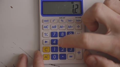 finger multiplying numbers using a calculator. closeup, overhead