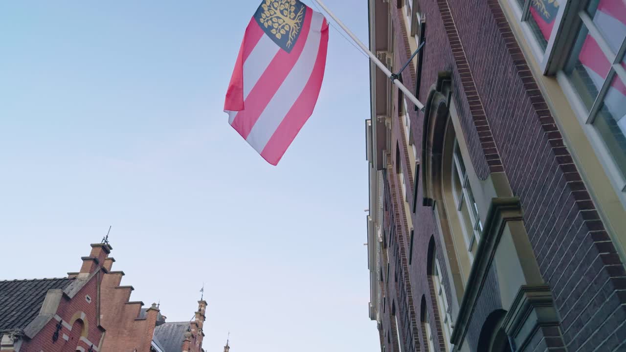 Street of the city town 's- Hertogenbosch Den Bosch with flag in Netherlands, low angle view of the buildings and authentic traditional Dutch European architecture style design