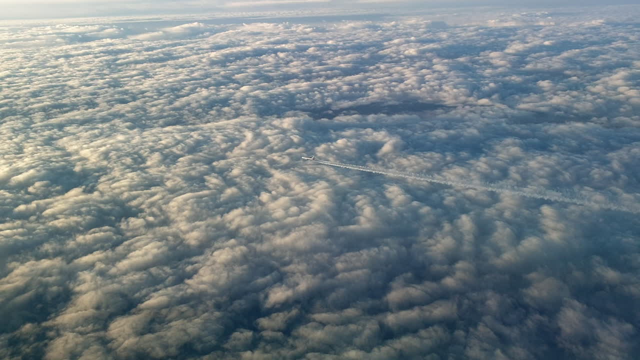 vista increíble desde la cabina de un avión que vuela alto por encima de las nubes dejando un largo rastro de aire de vapor de condensación blanco en el cielo azul