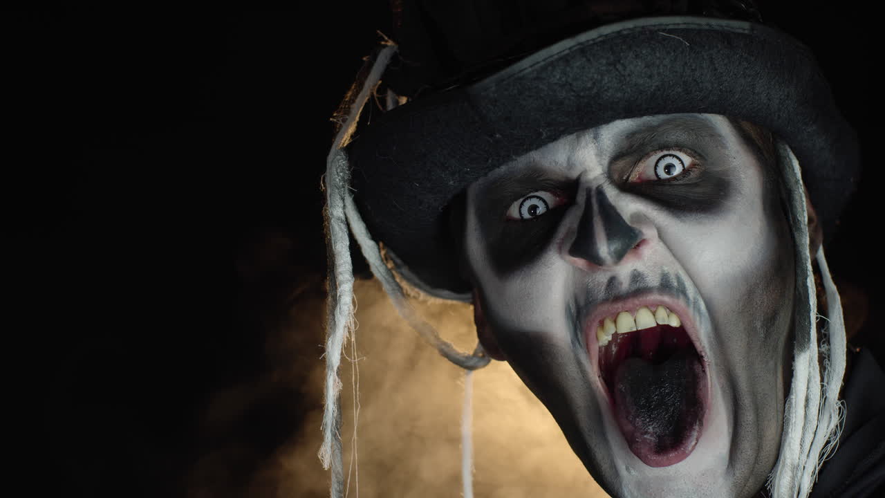 hombre aterrador en esqueleto maquillaje de halloween gira la cabeza y mira a la cámara con los ojos bien abiertos