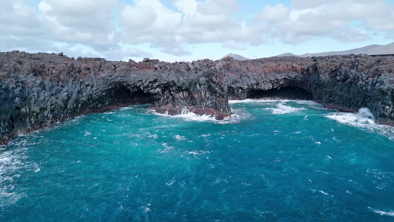 Powerful ocean waves crash violently into the volcanic cliffs of Los Hervideros in Lanzarote, Canary Islands.