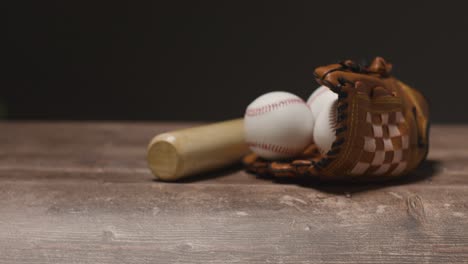 close up studio baseball still life with wooden bat and ball in catchers mitt on wooden floor