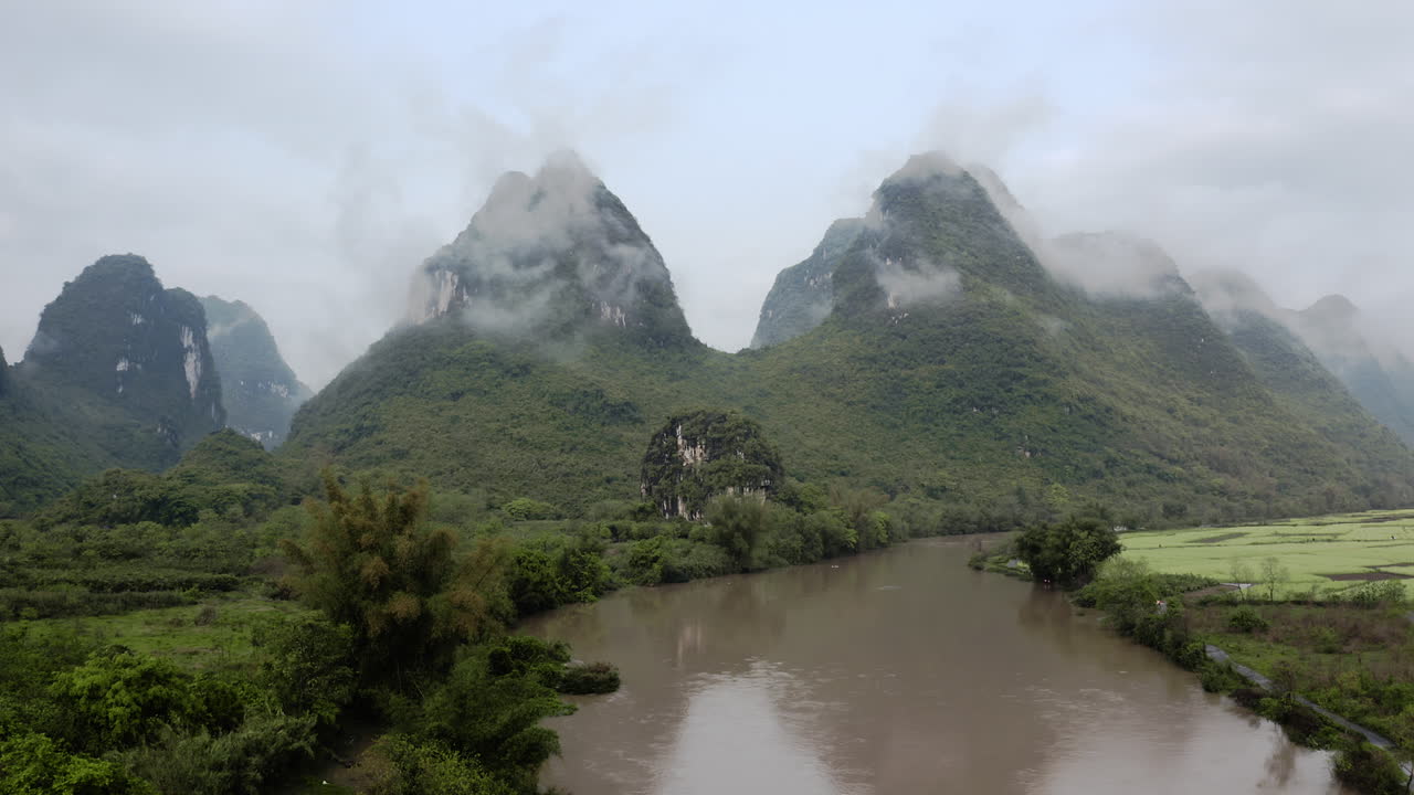 Murky muddy river flowing through karst mountain landscape, low aerial view