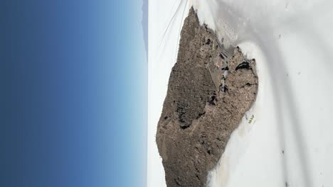 montaña marrón en el medio del desierto de salar de uyuni en bolivia, vertical aérea hacia atrás