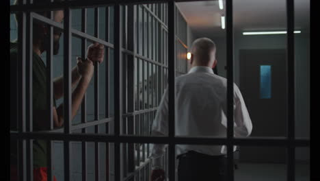 prison guard gives food to prisoner through metal bars          (stock footage)